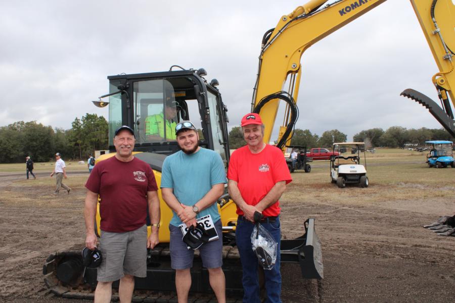 (L-R): Kevin Eddy and Robert Groff scope out the outside of this mini-excavator while Terry Groff (in cab) checks out the controls. The Groffs came to Florida from Copenhagen, N.Y.