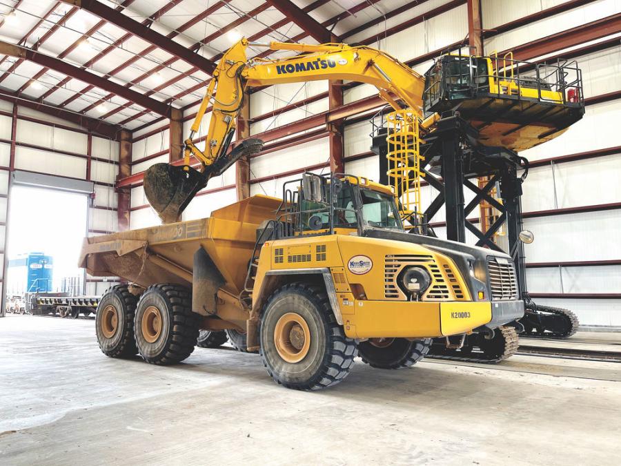 An operator for Waste Control Specialists loads a Komatsu HM400 truck with the company’s new customized PC360LC-11 straddle carrier.