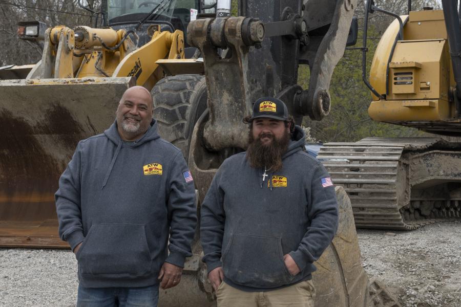 Chris Perreira (L) and Chris Perreira Jr. of ATW Line Painting & Construction LLC of Dighton, Mass., stand in front of their newly-purchased 2013 John Deere 225D excavator.
(CEG photo)