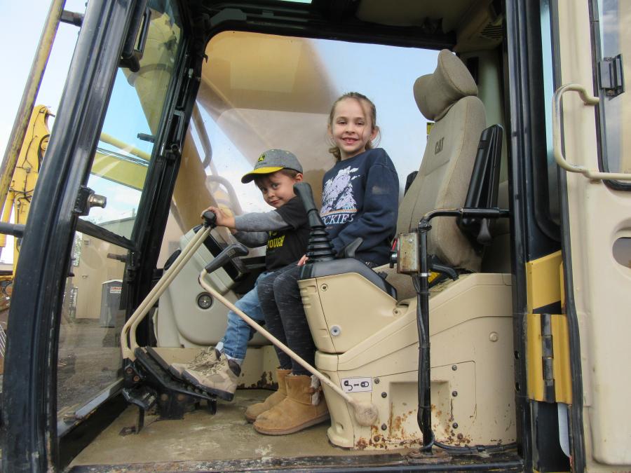 Milo (L) and sister, Annabelle, try out this 330L Cat excavator while their father, Rob Randall of Randall Brothers, considers a bid. 
(CEG photo)