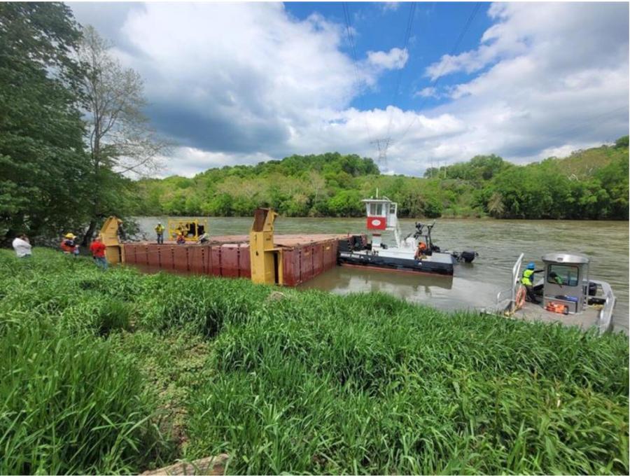 A tug boat moves a construction barge from Dam 4 where it had been stuck since breaking loose from its mooring following heavy rain. (Photo courtesy of National Park Service)
