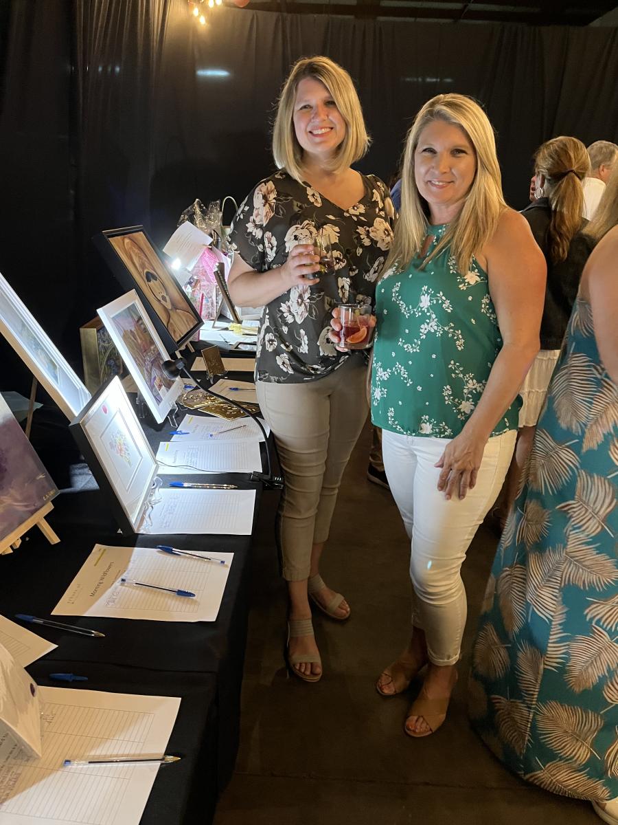 Shellie Larranaga (L) and Jennifer Bishop, both of Dynapac, check out the many wonderful items in the silent auction. (CEG photo)