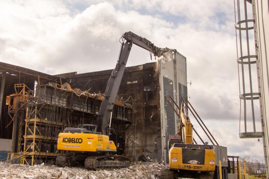 High reach excavators use shears and demolition processors to make exact cuts when demolishing structures.