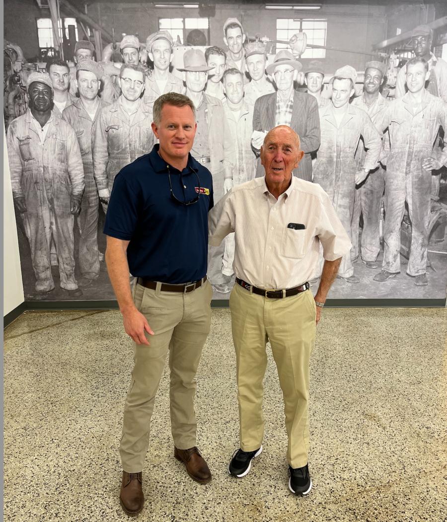 Neil Carbaugh (L) of Carolina Cat and Ed Weisiger, chairman Emeritus, Carolina Cat, stand in front of a photo of the team from the early days in the original Salisbury location.
(CEG photo)